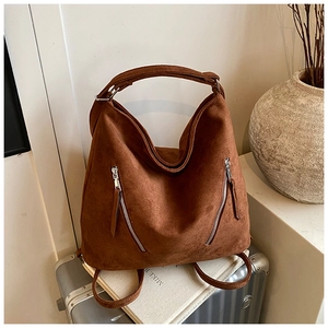 Détail du sac en daim marron foncé avec fermetures éclair argentées sur valise