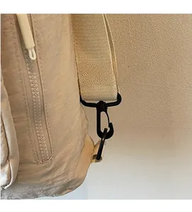 Detail of durable matte black metal hook and beige woven strap on nylon backpack