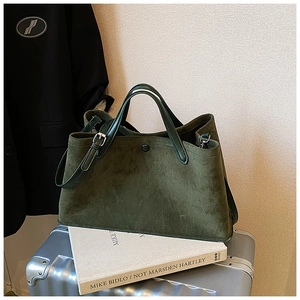 Close-up of a dark green matte suede tote bag on a silver suitcase for travel use