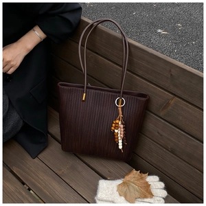 Dettaglio borsa shopper intrecciata marrone scuro con ciondolo in legno in stile autunnale