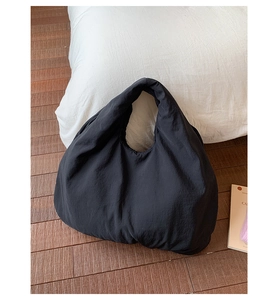 Macro view of black puffer tote bag showing textured nylon fabric and pleated surface details