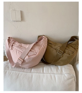 Quilted crescent shoulder bags in pink and khaki displayed on a minimalist sofa