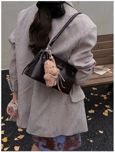 Détail d'un sac à main marron en cuir brillant avec ourson et chaîne de perles