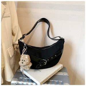 Detail of black canvas crescent bag with leather eyelet strap and plush dog charm