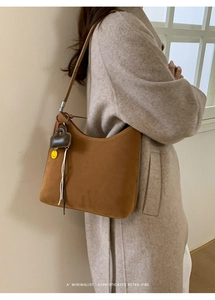 Detailed view of a retro brown suede tote bag with heart charms and fringe tassel detail