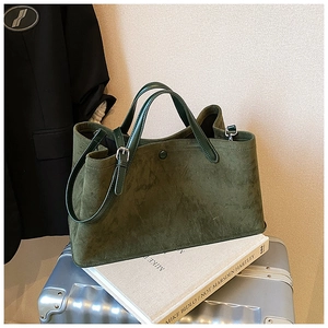 Detailed macro view of dark green suede tote bag showing magnetic clasp and inner lining