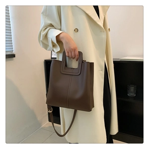 Detail of dark brown leather tote bag with integrated handle and adjustable strap