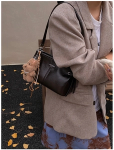 Détail d'un sac à main en cuir marron foncé avec un ours en peluche et boucles argent