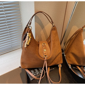 Detail of a brown matte suede hobo bag featuring flower buckle and boho wood bead charm