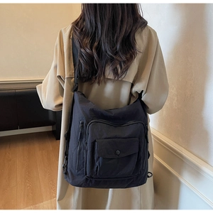 Close-up of black nylon crossbody bag with multi-pocket details and wide strap