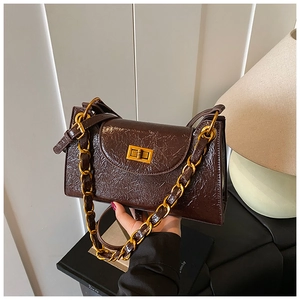 Close-up of a brown wrinkled leather handbag featuring a bold gold chain and turn-lock