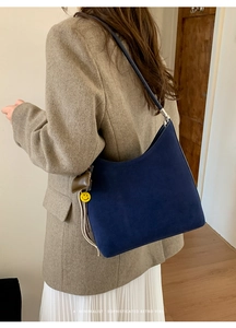 Detail of dark blue suede hobo bag featuring a retro half-moon shape and side charms