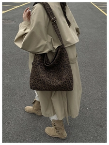 Detail shot of leopard print tote bag showing wide strap on model with trench coat