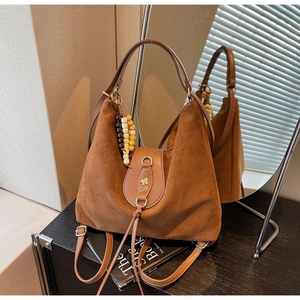 Macro detail of brown frosted leather tote bag with floral metal lock and wooden beads