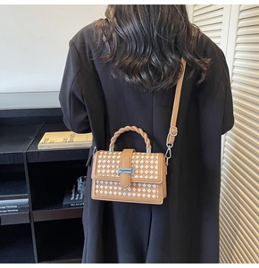 Detail of woven square bag with spiral handle and metallic H-clasp on model