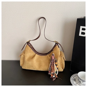 Detail of suede crescent bag with boho tassel pendant and leather straps
