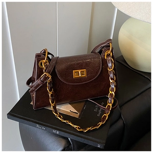 Close-up of vintage dark brown oil wax leather handbag with golden twist-lock closure