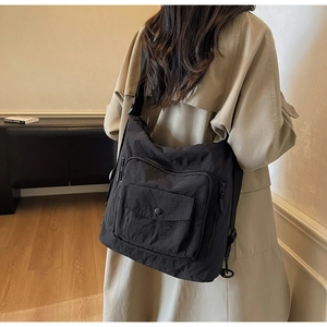 Close-up of black nylon multi-pocket tote bag with wrinkled texture and zipper details