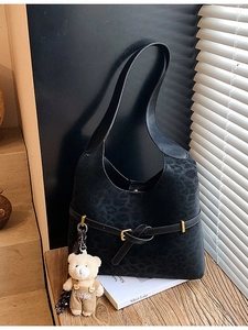 Black leopard print tote bag with matte texture and cute plush bear accessory on strap