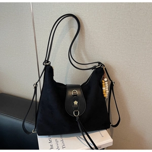 Detail of black frosted tote bag with gold flower buckle, long tassels and wooden beads