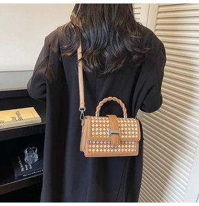 Detail of woven pattern on brown and white checkered handbag with silver metal buckle
