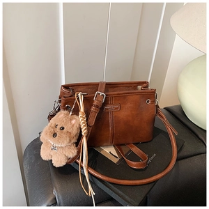Détail d'un sac bandoulière vintage en cuir PU marron avec charme de chien en peluche doux
