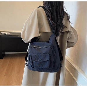 Detail of dark blue nylon crossbody bag with multiple zipper pockets on a female model