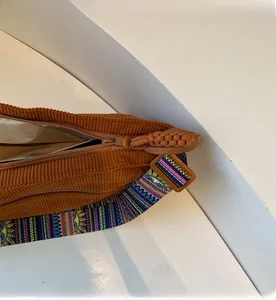 Detail of smooth zipper closure on brown corduroy bag with ethnic woven strap