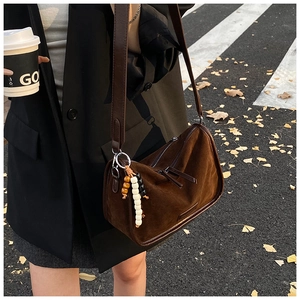 Details einer braunen Wildleder-Halbmondtasche mit bunten Perlen und langem Lederriemen