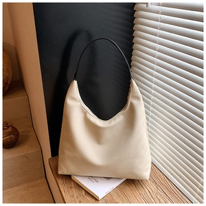 Sac sous le bras beige minimaliste avec bandoulière noire sur fond de fenêtre à persiennes