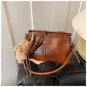 Gros plan d'un sac bandoulière vintage en cuir marron avec breloque ours et boucle en métal