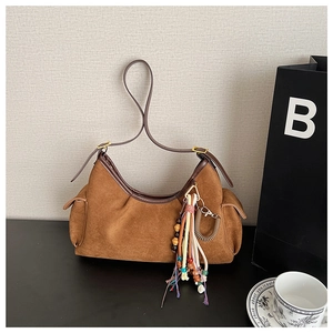 Detail of dark brown suede hobo bag with ethnic tassel pendant and adjustable strap