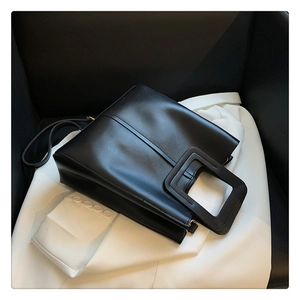 Detail of square cutout handle and smooth matte leather finish on black tote bag