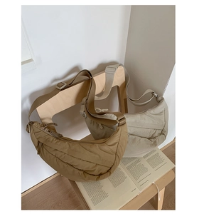 Detailed macro view of quilted nylon crescent bags in warm brown and cream white colors