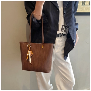 Dettaglio borsa tote vintage marrone con texture a coste e ciondolo con nappa e perline