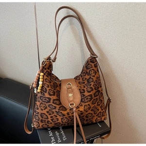 Close-up of leopard print tote bag with brown leather strap and metal flower buckle