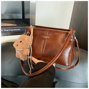 Détail d'un sac à main vintage en cuir marron avec un charme de chien en peluche
