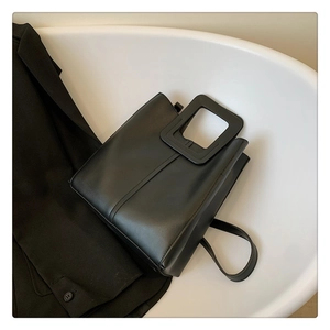 Detail of minimalist black tote with square cutout handle and smooth matte leather finish