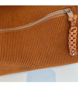 Close-up of the brown corduroy fabric texture with a sturdy metal zipper and woven puller