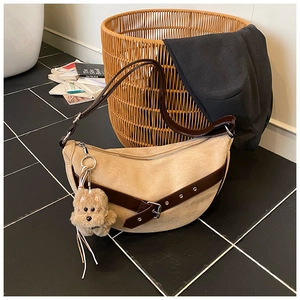 Detail of khaki suede crescent bag with dark brown leather strap and puppy charm