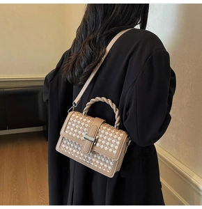Close-up of woven square handbag featuring checkered texture and braided handle
