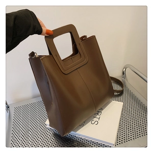 Detail of dark brown PU leather tote bag with square cutout handle and crossbody strap