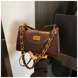 Close-up of caramel brown shoulder bag with shiny gold chain and luxury texture