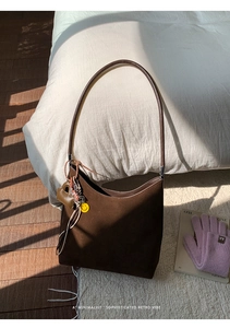 Brown suede hobo bag detail with leather heart charm and yellow smiley face accessory