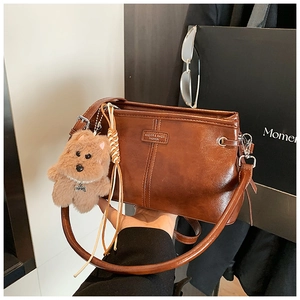 Détail du sac à main rétro en cuir verni marron avec pendentif chien en peluche
