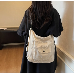 Detail of beige canvas messenger bag showing multi-pocket design and adjustable strap
