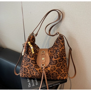 Close-up of leopard print tote bag featuring golden flower hardware and beaded tassel detail