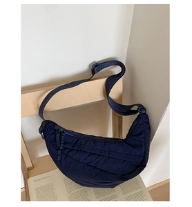 Close-up of dark blue quilted crescent bag on a wooden chair for a cozy lifestyle feel