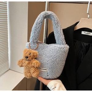 Détail du sac seau en peluche bleu clair avec un joli pendentif ours marron attaché