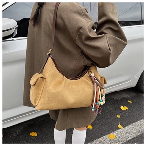 Detailed view of yellow suede hobo bag with tassel charms and side pocket feature